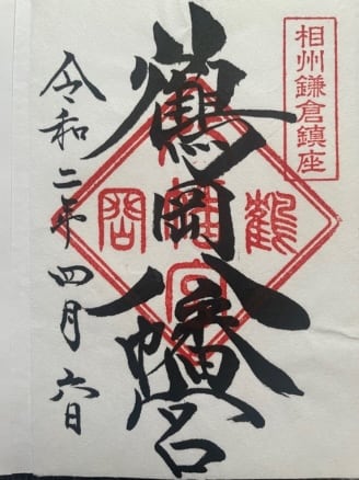 A piece of white paper with black Japanese calligraphy and red seal stamps evokes the serene beauty of Kamakura.